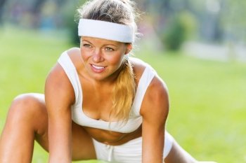 Outdoor workout. Young sport woman in white stretching in park
