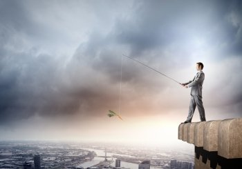 Businessman with rod. Young businessman standing on top of building and fishing