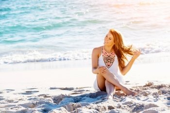 Young woman sitting on the beach. Portrait of young pretty woman  sitting on sandy beach