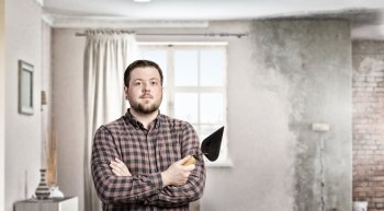 Home renovation and improvement. Man in checked shirt indoors with spatula in hand