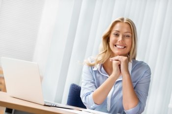 Businesswoman smiling and sitting in offfice