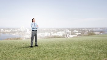Confident businessman outdoors. Businessman standing on green grass with his arms crossed 