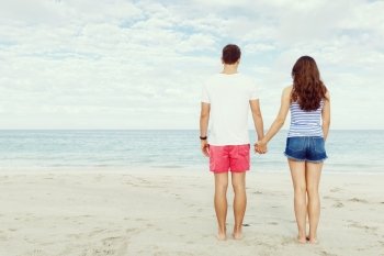 Romantic young couple standing on the beach. Romantic young couple standing on the beach looking at the ocean