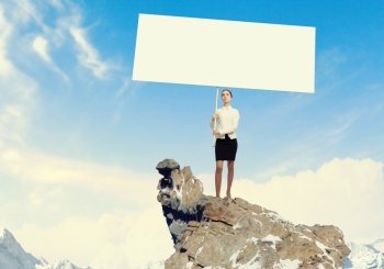 Business woman with banner. Image of business woman standing atop of hill holding blank banner