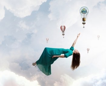 Woman floating in sky. Elegant woman in green long dress floating in sky. Elements of this image are furnished by NASA
