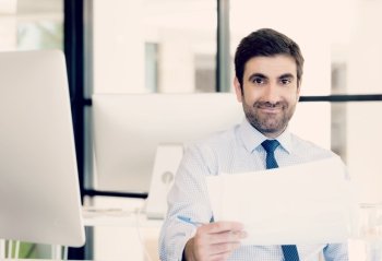 Handsome businessman with papers in office