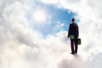 Success in business. Back view of businessman standing on cloud high in sky