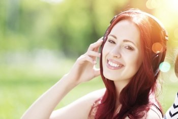 Sounds of nature. Young pretty woman enjoying music in headphones in summer park