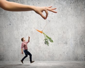 Man in casual chased with carrot hanging on rope. Motivation concept