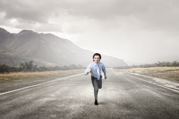 Businessman run on road. Young businessman in suit running outdoor on asphalt road