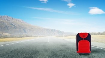 Red suitcase on road. Travel concept with red suitcase on road