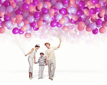 Happy young family. Happy young family walking holding bunch of colorful balloons