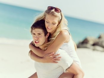 Portrait of man carrying girlfriend on his back. Portrait of man carrying girlfriend on his back on the beach
