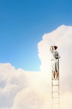 Businesswoman standing on ladder. Businesswoman standing on ladder looking into distance against cloudy background
