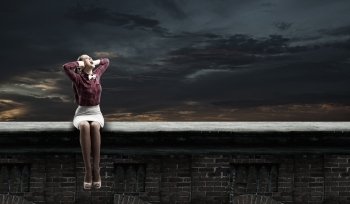 Stop  that sound!. Young woman sitting on roof and covering ears with hands