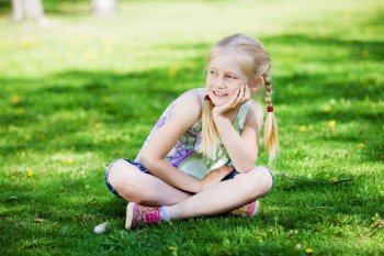 Little girl in park. Image of little cute girl sitting on grass in park