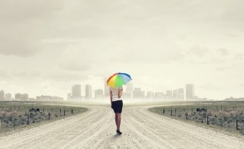 Woman with rainbow umbrella. Young pretty businesswoman with rainbow colorful umbrella walking on road