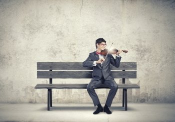 Man playing violin. Young man in suit sitting on bench and playing violin