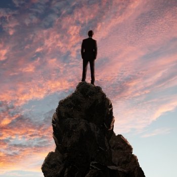 Image of a businessman standing on the top of a high mountain