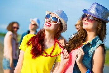 Two young girls. Image of two attractive young women in bright clothes having fun outdoors