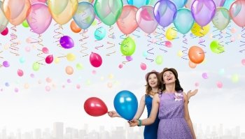 Preparing great party. Two young woman in casual with colorful balloons celebrating