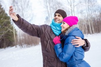 Selfie in park. Happy young couple in winter park having fun