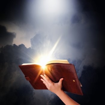 Magic book. Human hand holding magic book with magic lights