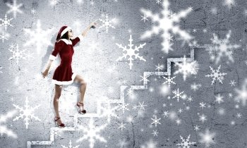 Santa girl. Attractive young woman in Santa suit walking on ladder