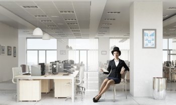 Businesswoman on chair in office. Elegant businesswoman in suit and hat sitting on chair in office interior