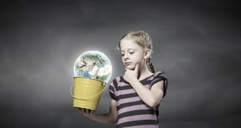 Kid with bucket. Cute girl looking at Earth planet in her bucket. Elements of this image are furnished by NASA