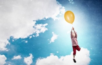 Happy careless childhood. Little happy cute boy flying on balloon