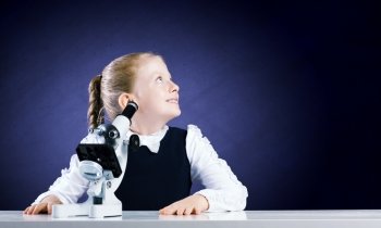 School education. Cute school girl with microscope in classroom