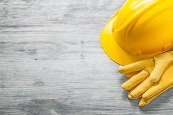 Yellow hard hat protective gloves on wooden board copy space construction concept.