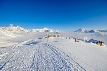 Ski lift station in mountains at winter. Alpine winter mountain landscape. French Alps covered with snow in sunny day. Val-d'Isere, Alps, France