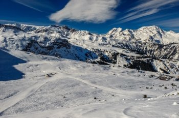 Alpine winter mountain landscape. French Alps covered with snow in sunny day. Meribel, France.