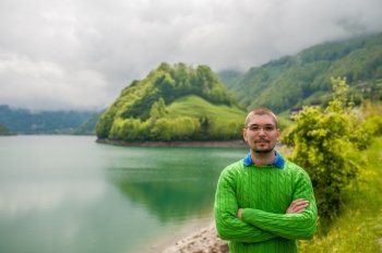 Man at beautiful emerald mountain lake Lungern in Switzerland under low clouds