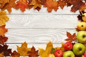 Autumn leaves and apples over old wooden background with copy space