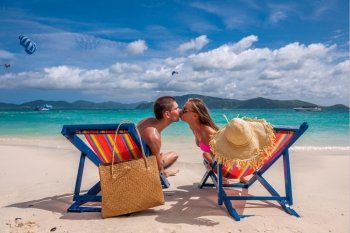 Couple kissing on tropical beach in loungers at Thailand