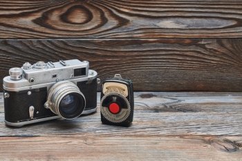 Vintage old retro 35mm rangefinder camera and light meter. Vintage old retro 35mm rangefinder camera and light meter on wooden background with copy space