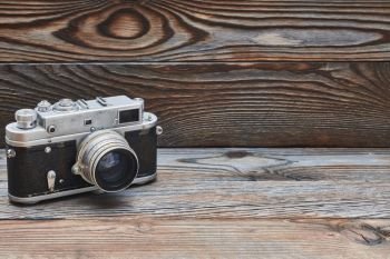 Vintage old retro 35mm rangefinder camera on wooden background with copy space 