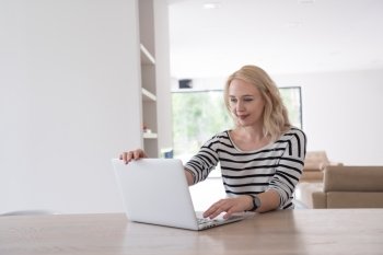 Young woman with her laptop computer in her luxury modern home, smiling