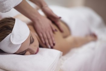 Close up image of a young woman who laying on her stomach and receiving a back massage