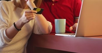 Couple sitting at table making online purchase using credit card