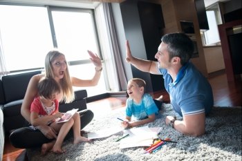 Happy Young Family Playing Together at home on the floor using a tablet and a children’s drawing set