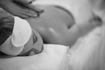 Close up image of a young woman who laying on her stomach and receiving a back massage