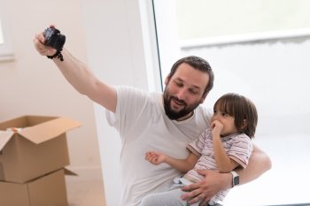 young father and his son photographed themselves with cardboard boxes around them while moving into their new home