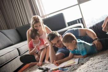 Happy Young Family Playing Together at home on the floor using a tablet and a children’s drawing set