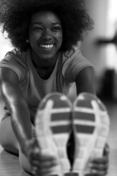 happy young african american woman in a gym stretching and warming up before workout