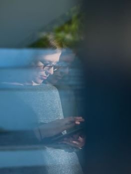Woman using tablet computer at home, close up shot through window