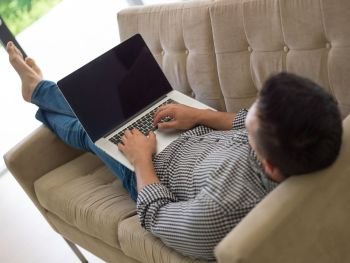 Young, handsome man using laptop sitting on sofa